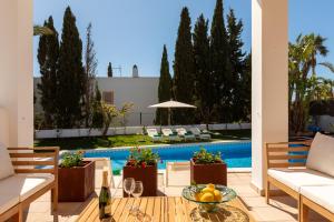 a patio with a table and chairs and a pool at New! Villa Lina in Santa Gertrudis de Fruitera