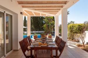 a dining table and chairs on a patio with a pool at New! Villa Lina in Santa Gertrudis de Fruitera