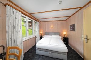 a bedroom with a bed and a window at Jungfrau Lodge, Swiss Mountain Hotel in Grindelwald