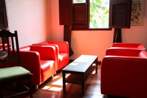 a waiting room with red chairs and a table at casaJOMO in Rio de Janeiro