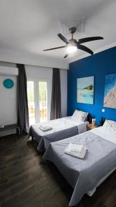 a bedroom with two beds and a ceiling fan at House with a pool, 2' from the beach in Kineta +99 photos