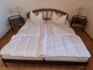 a bed with white sheets and pillows on it at Sundby in Lemkenhafen auf Fehmarn