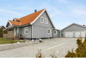 a gray house with an orange roof and a parking lot at حورية البحر in Bromölla