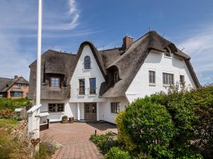 a large white house with a thatched roof at Hotel Duene in Rantum