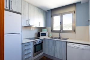 a kitchen with white cabinets and a sink and a microwave at Les nid doré suites in Roses