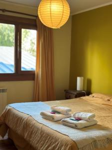 a bedroom with a bed with two towels on it at Hosteria Miyazato Inn in El Calafate