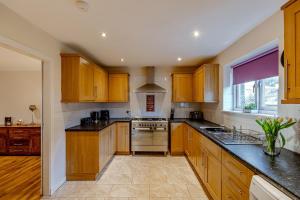 a kitchen with wooden cabinets and black counter tops at Ballo Cottage - Stunning views in Leslie