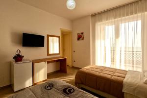 a bedroom with a bed and a desk and a television at Hotel Brilant in Shëngjin