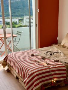a bed with a striped blanket in a room with a window at Studio cosy - Porte de Genève & Voie Verte in Ambilly
