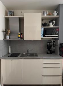a kitchen with white cabinets and a sink and a microwave at Gode Wind in Eckernförde +6 photos