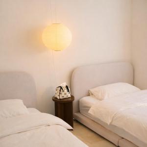 a bedroom with two beds and a table with a lamp at Stay Noop in Gyeongju