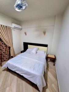 a bedroom with a large bed with white sheets at Monument Pyramids View in Cairo