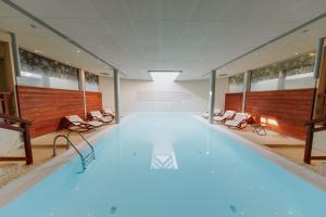 a large swimming pool with chairs in a building at Hôtel Au Chamois d'Or by Les Etincelles in L'Alpe-d'Huez