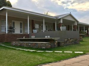 a brick house with a porch on a lawn at Anathi Hotel in Kokstad