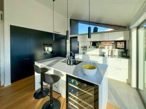 a kitchen with a sink and a counter with stools at Idyllic Modern House Overlooking Lammefjord in Vig