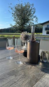 two glasses and a bottle of wine on a wooden table at Landgasthof Brandtner Wirt in Langdorf
