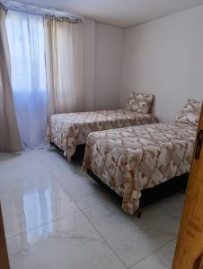 a bedroom with two beds and a chair and a window at Hotel Borza Carneiro in Piraí do Sul