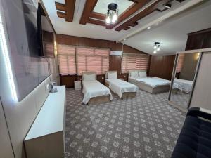 a room with two beds and a flat screen tv at Al Samarqandi Hotel in Samarkand