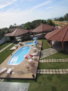 uma vista superior para uma piscina com cadeiras e guarda-sóis em Pousada Tropical em Prado