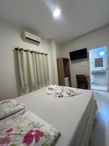 a bedroom with two beds and a flat screen tv at Hotel Santa Clara in Aparecida