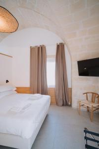 a bedroom with a white bed and a window at Cavae - Le stanze in Massafra