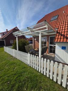 a white fence with a pergola on a house at Ferienhaus Seemöwe mit Deichblick Butjadingen-Burhave in Burhave