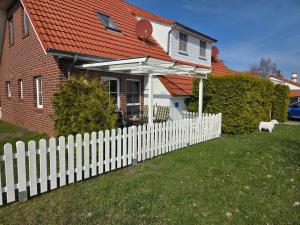 a white picket fence in front of a house at Ferienhaus Seemöwe mit Deichblick Butjadingen-Burhave in Burhave