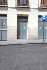 a building with three glass doors and a parking sign at Cubik Rooms in Madrid