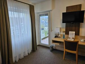 a hotel room with a desk and a window at Hotel Zum Holländer in Lindlar