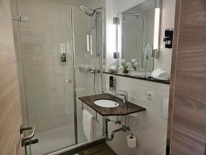 a white bathroom with a shower and a sink at Hotel Zum Holländer in Lindlar