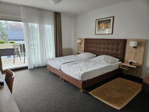 a bedroom with a large bed and a balcony at Hotel Zum Holländer in Lindlar