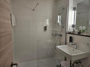 a white bathroom with a shower and a sink at Hotel Zum Holländer in Lindlar +2 photos
