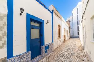 a blue door on a white building in an alley at Casa Margot Old Town Rooftop Walk Promenade in Portimão