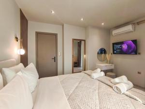 a bedroom with a large white bed with a tv on the wall at Meteora Gaia in Kastraki