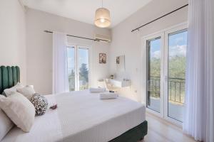 a white bedroom with a bed and a large window at The 7 Trees Apartments by Konnect, Nisaki in Nisaki