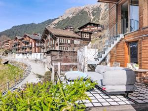 a patio with a couch and chairs on a balcony at Apartment Roossi Apt- 1 by Interhome in Wengen