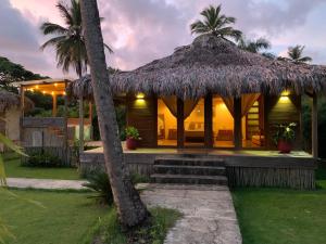 a villa with a thatch roof and a house at Palmeras del valle in La Majagua