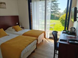 ein Hotelzimmer mit zwei Betten, einem Schreibtisch und einem Fenster in der Unterkunft Hôtel Le Trécelin in Frehel + 35 Fotos