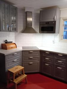 a kitchen with gray cabinets and a wooden stool at Herrgårdsvillan in Tjurkö