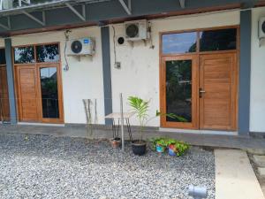 a house with wooden doors and plants in front of it at Cozzee AnD in Labuan Bajo