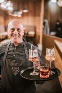 a man holding a tray with two glasses of wine at Berghotel Kleiner Biber in Warth am Arlberg