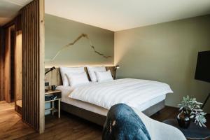 a bedroom with a large white bed and a wall with a chart at Berghotel Kleiner Biber in Warth am Arlberg