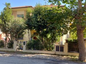 a yellow house with a fence and trees at Domus Le Palme in Fano