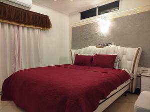 a bedroom with a large bed with a red blanket at Mon Nid d'Or ABIDJAN CI in Abidjan