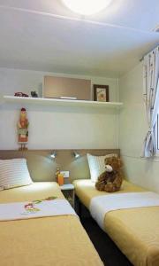 a room with two beds with a teddy bear sitting on the bed at Mobile Homes Victoria San Marino in Lopar
