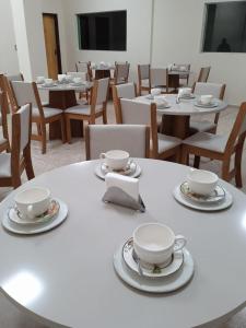 a white table with two cups and saucers on it at Hotel Borza Carneiro in Piraí do Sul