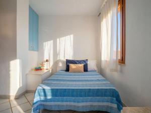 a bedroom with a blue and white bed with a window at Apartment Rais 13 by Interhome in Stintino
