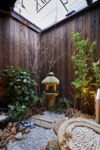 a small garden with a birdbath in front of a wooden fence at Miro Hachijo Uchidacho Tei in Kyoto