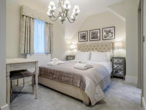 a bedroom with a bed and a desk and a chandelier at 2 Bed in Chipping Campden oc-78128 in Chipping Campden