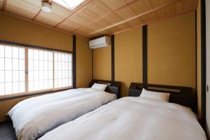 two beds in a room with two windows at Miro Hachijo Uchidacho Tei in Kyoto